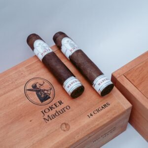 Two dark Joker Maduro cigars resting on a wooden cigar box.